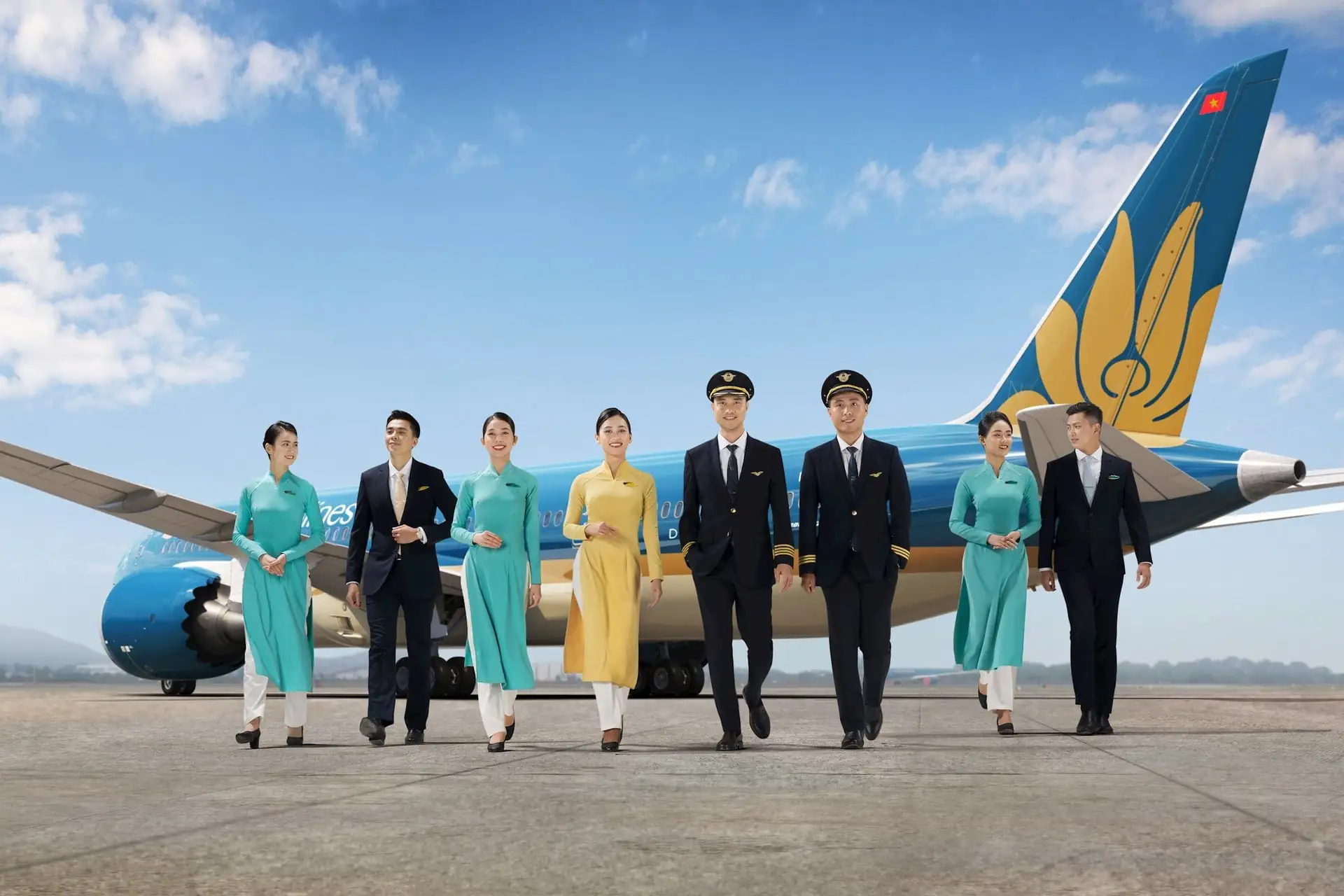Máy bay Vietnam Airlines màu xanh với bông sen vàng, cờ Việt Nam và đội tiếp viên tại sân bay